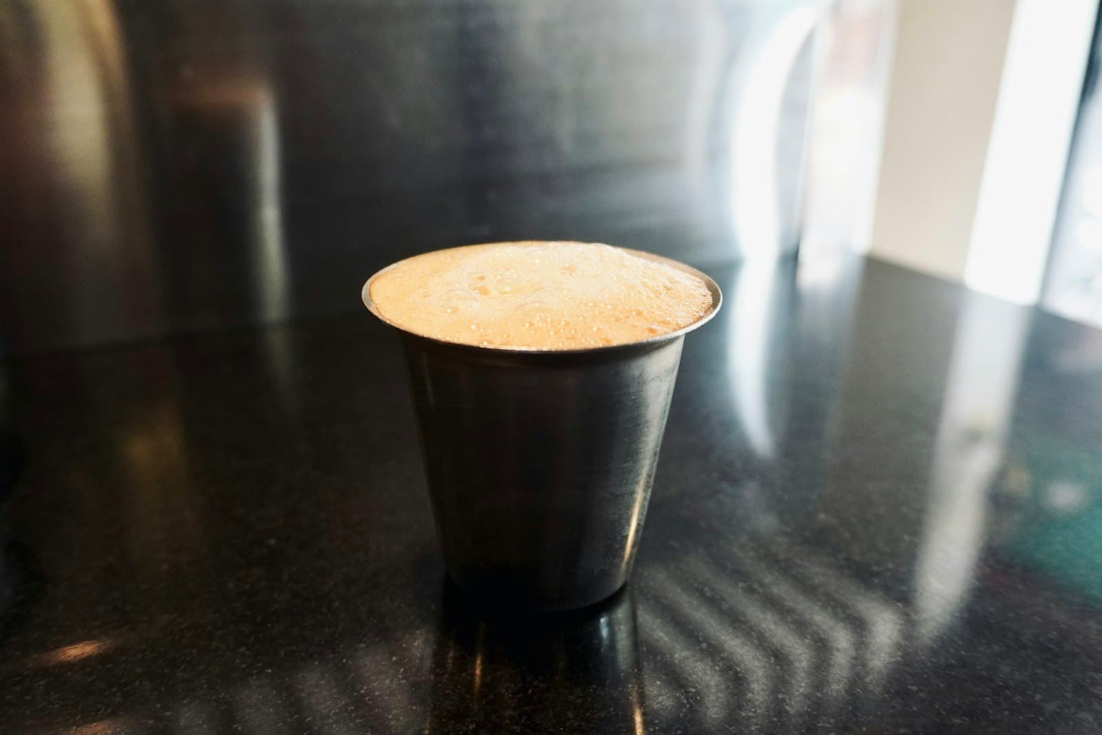 A steel tumbler of frothy South Indian filter coffee